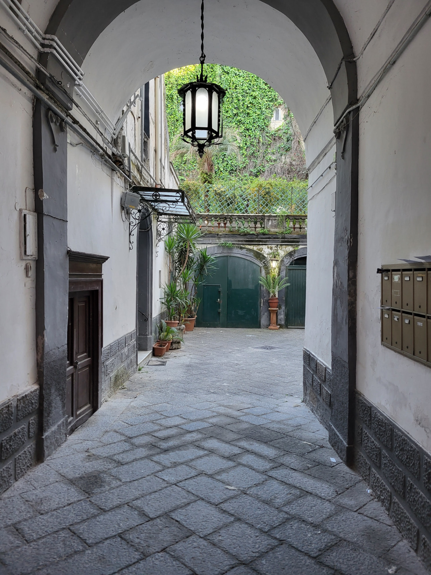 Cortile interno del palazzo con lanterna d'epoca e piante mediterranee, Centro Storico di Napoli