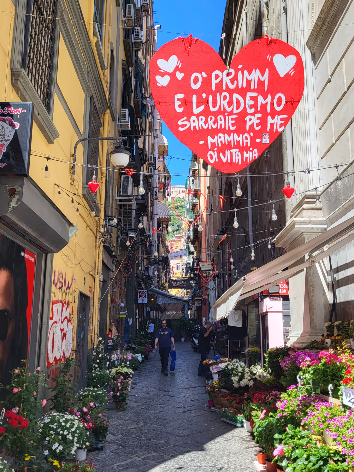 Vicolo caratteristico del Centro Storico di Napoli con banchi di fiori e decorazioni
